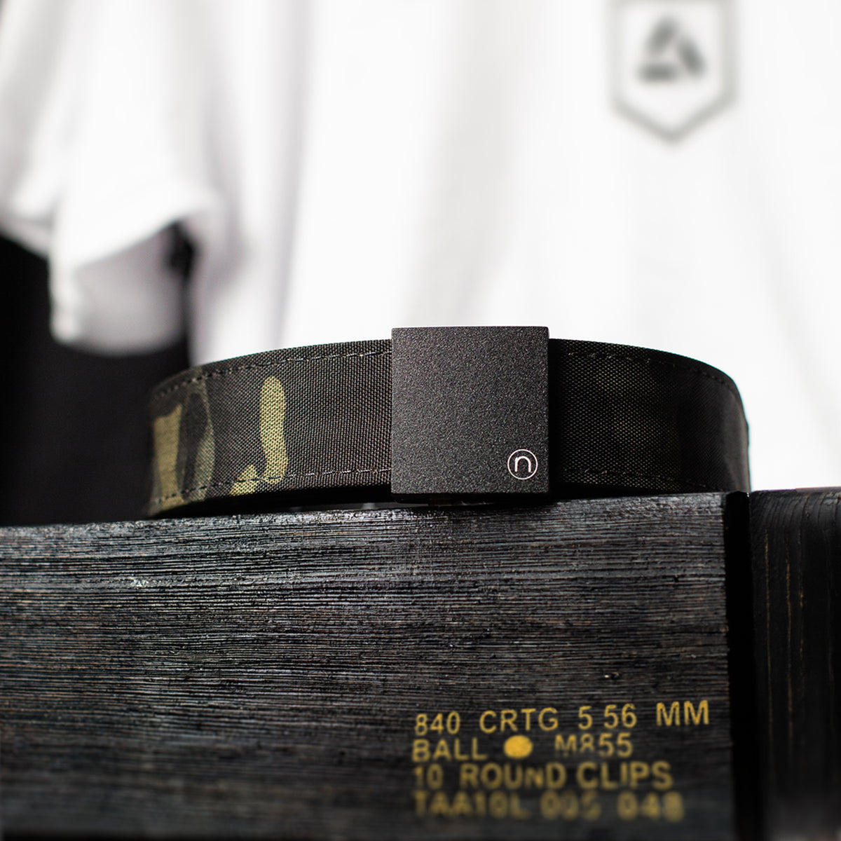 MultiCam Black EDC ratchet belt displayed on an ammunition crate