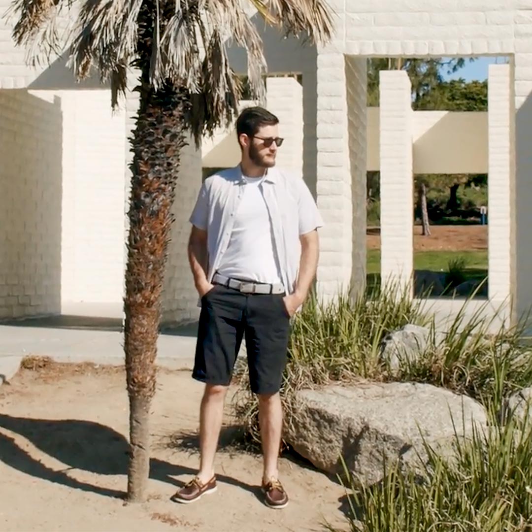 Man wearing a cool grey belt standing next to a palm tree